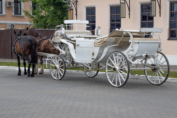 A white horse-drawn carriage with two horses, waiting for tourists on the old town square at the...