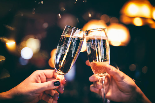 Two Glasses With Sparkling Champagne Wine In Hands, Concept For Holiday, Wedding Valentines Christmas And New Year, Bokeh, In A Restaurant And Cafe