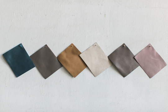 Neutral tone leather cowhide swatches on white wall, copy space