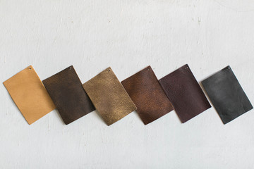 neutral brown and black leather cowhide swatches on white wall, copy space