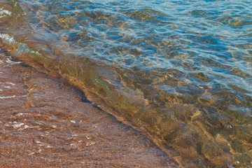Clear water texture in blue and orange. Background of the ocean and the sea backlit by the sun. Soft waves. Natural water