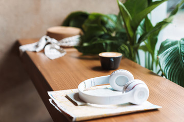 Image of cup of coffee, headphones, passport, paper map on wooden table