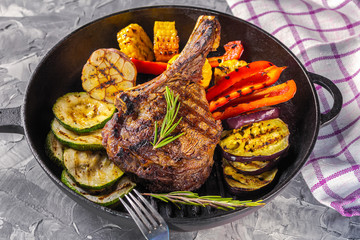Juicy steak with grilled vegetables served in a cast iron pan. Life style. Top view.