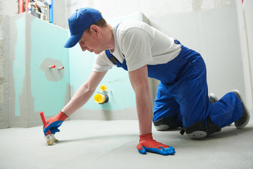 Floor waterproofing in bathroom. Worker adding цater resistant, protective coating