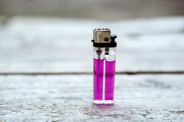 Close up of a pink lighter on a wooden background. - obrazy, fototapety, plakaty