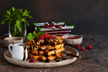 Homemade waffles with chocolate sauce and berries on the kitchen table.