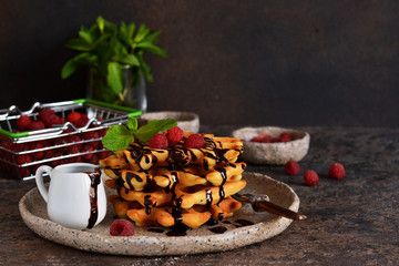Homemade waffles with chocolate sauce and berries on the kitchen table.