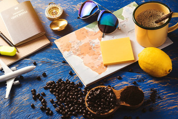 accessories for the traveler on the old background on the on blue wood table. Travel concept using world map and compass along with other travel accessories. Hot coffee and beans. summer
