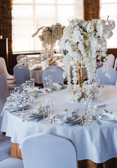 banquet round tables, decorated with a bouquet of white flowers in the center of the tables
