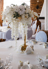 banquet round tables, decorated with a bouquet of white flowers in the center of the tables