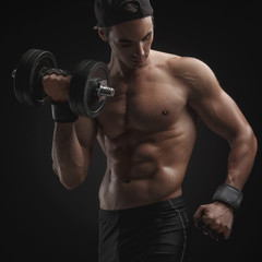 Athletic young man doing exercises with a dumbbell