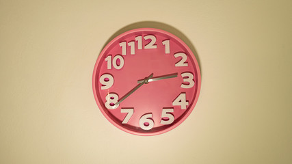 Pink clock with a white wall hanging on the wall