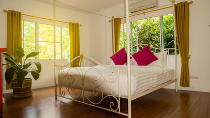 The bed has white sheets and pink pillows with glass windows on both sides.