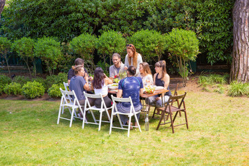 Friends in sportswear eating outdoors. Sporty young male and female friends gathering around table and eating healthy dishes in backyard. Healthy lifestyle concept