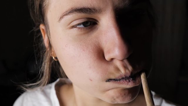 A woman brushes her teeth with black whitening paste with charcoal, a bamboo eco-friendly toothbrush made of wood.