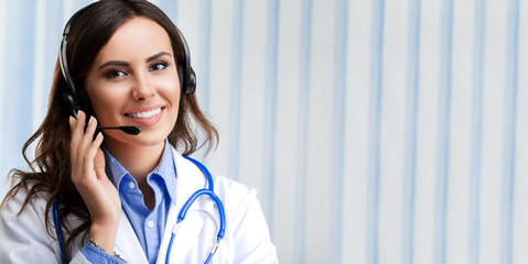 Portrait of happy smiling young doctor in headset, at office, with blank copyspace area for slogan...