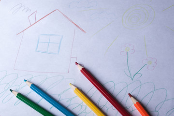 children's drawing and colored pencils lie on the table. children's creativity. children's problems. the child dreams of a cozy house.