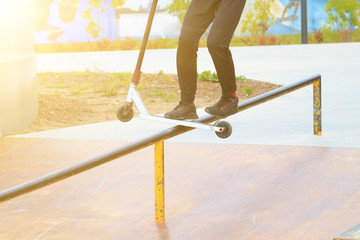 rider on stunt kick scooter slides along edge of metal ramp in skate park