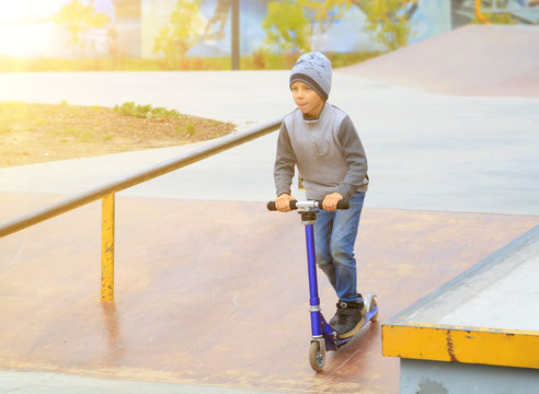 Boy On Kick Scooter Trains To Ride And Perform Tricks Like Older Guys In Skate Park