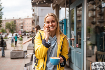 Enchanting blonde young woman with smartphone while on the street