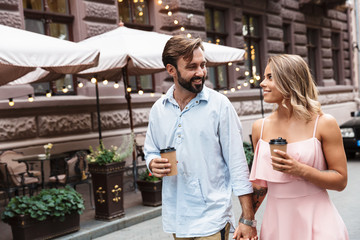 Beautiful young couple walking outdoors along the city street