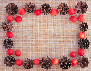 Autumn. Frame of pine cones and paradise apples on a beige background.