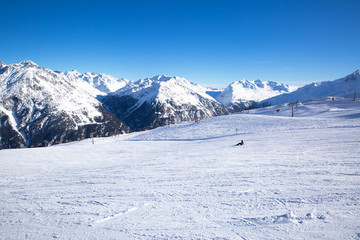 Ski slopes covered by snow in winter season. Alp mountains. Bright winter day with blue sky. 