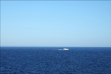 Horizon in the sea with ship away in blue haze..