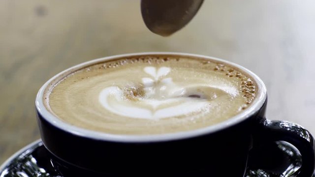 Putting a teaspoon of sugar to latte and stirring