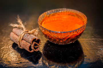Cinnamon and honey hair mask in a glass bowl on a wooden surface with gold lights isolated. Along...