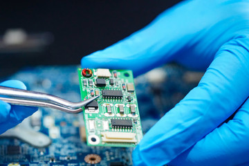 Ttechnician repairing inside of hard disk by soldering iron. Integrated Circuit. the concept of...