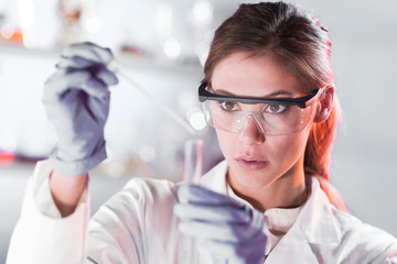 Life scientists researching in laboratory. Focused female life science professional pipetting...