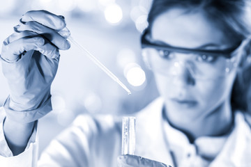 Life scientists researching in laboratory. Focused female life science professional pipetting...