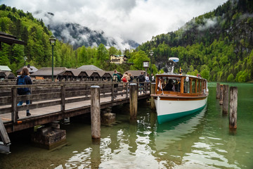Scenic view on Konigssee Lake with wooden pier with moored touristic ship