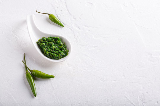 Hot chili pepper paste. Green sauce on white background. Adjika or ajika in Georgian cuisine or harissa in Arabic cuisine. Top view.