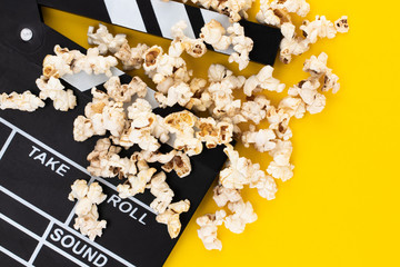 Popcorn and clapperboard on colorful background. Top view.