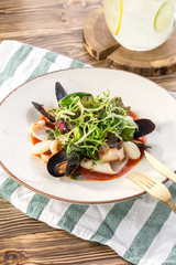 Tasty seafood with green salad mix on white plate on wooden table