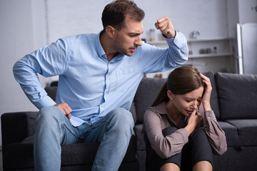 aggressive man in shirt beating scared wife during quarrel