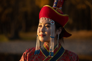Beautiful young woman posing in traditional Mongolian dress in sunset light. Ulaanbaatar, Mongolia.