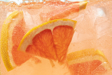Close up view of the lemon and grapefruit slices in lemonade background. Texture of cooling sweet...