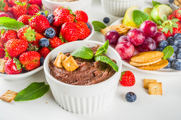 Vegan food for breakfast, snack. Homemade Sweet Hummus with strawberries, apple, crackers, grapes. Variations of different hummus dessert dips - vanilla, chocolate, caramel.