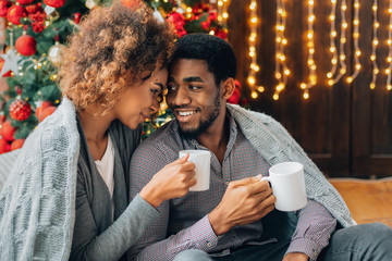 Young couple drinking coffee at Christmas tree