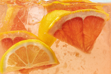 Close up view of the lemon and grapefruit slices in lemonade background. Texture of cooling sweet...