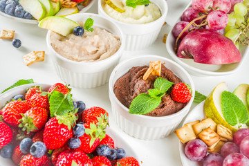 Vegan food for breakfast, snack. Homemade Sweet Hummus with strawberries, apple, crackers, grapes. Variations of different hummus dessert dips - vanilla, chocolate, caramel.