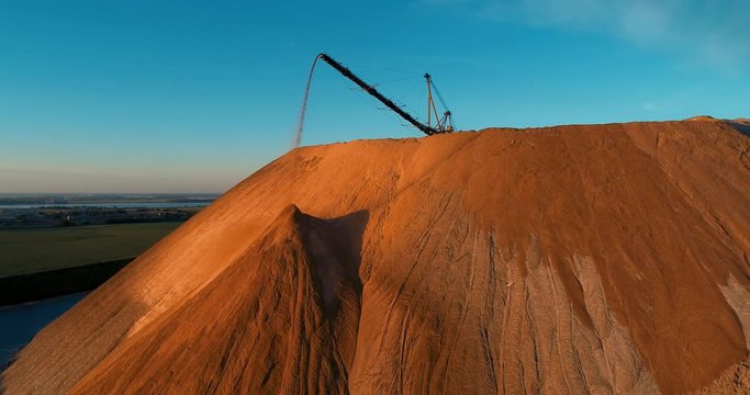 Mountains tailing piles and water basins. Waste left after potash salt ore extraction from underground mines falling from the conveyor belt. Environmental pollution from industrial production.