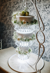 three-level wedding cake on a decorative stand with hanging levels