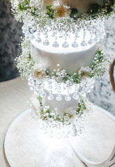 three-level wedding cake on a decorative stand with hanging levels