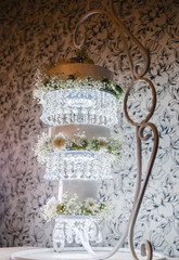 three-level wedding cake on a decorative stand with hanging levels