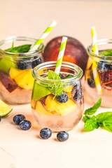 Blueberry and peach infused water, cocktail, lemonade or tea. Summer iced cold drink with blueberry, lime, peach and mint