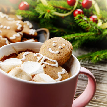 Pink mug with hot chocolate marshmallows and gingerbread man closeup